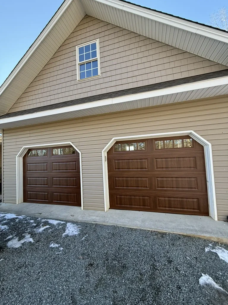 Newly installed dual insulated garage doors with windows on a tan home in Salem, VA, with Ferguson’s service truck parked nearby