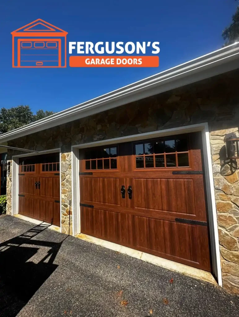 Newly installed dual insulated carriage style garage doors with windows on a home